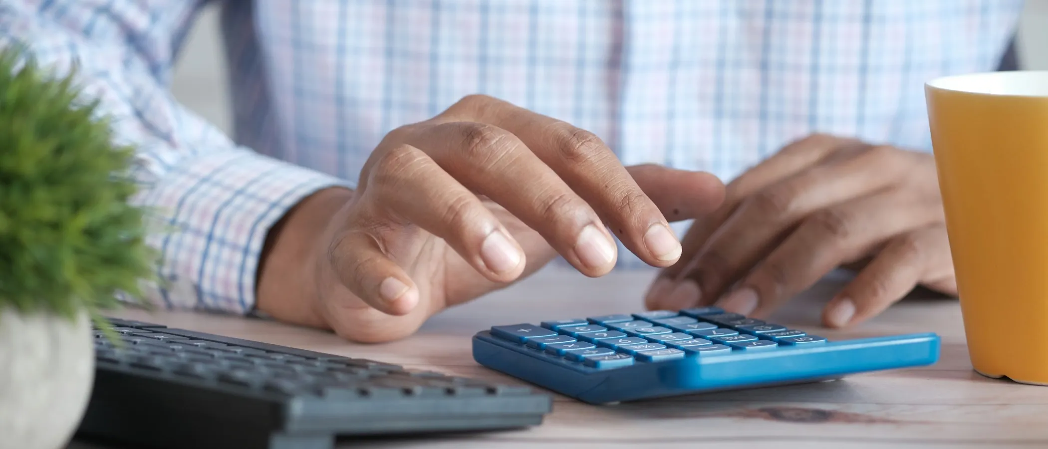 A bookkeeper working through figures on a desk calculator beside a keyboard